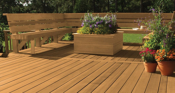 Outdoor wood deck with benches and flower planters, highlighting a well-protected surface with a natural wood grain appearance.