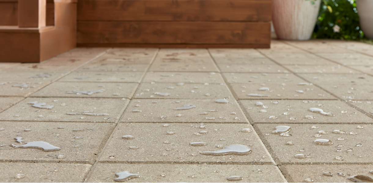 Close-up of a stone surface with water droplets beading up, demonstrating the effectiveness of a sealant in repelling moisture.